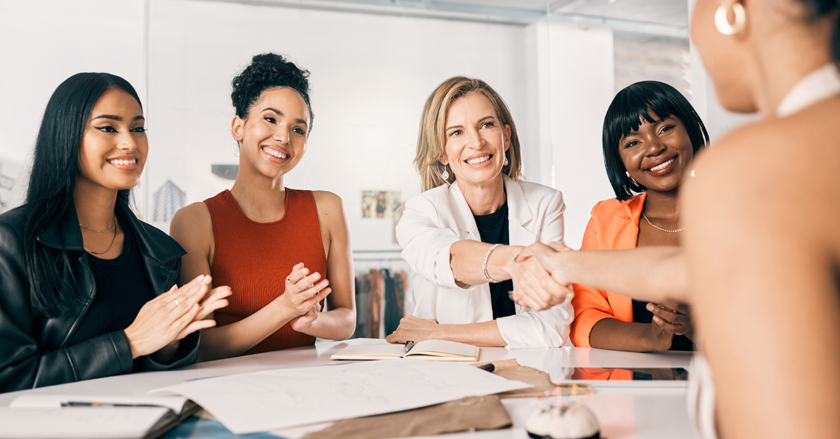 smiling women sitting at a conference table